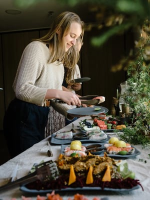 Smiling woman serves herself nourishing seasonal food from a wellness lunch buffet at Peninsula Hot Springs’ Wellness Centre.