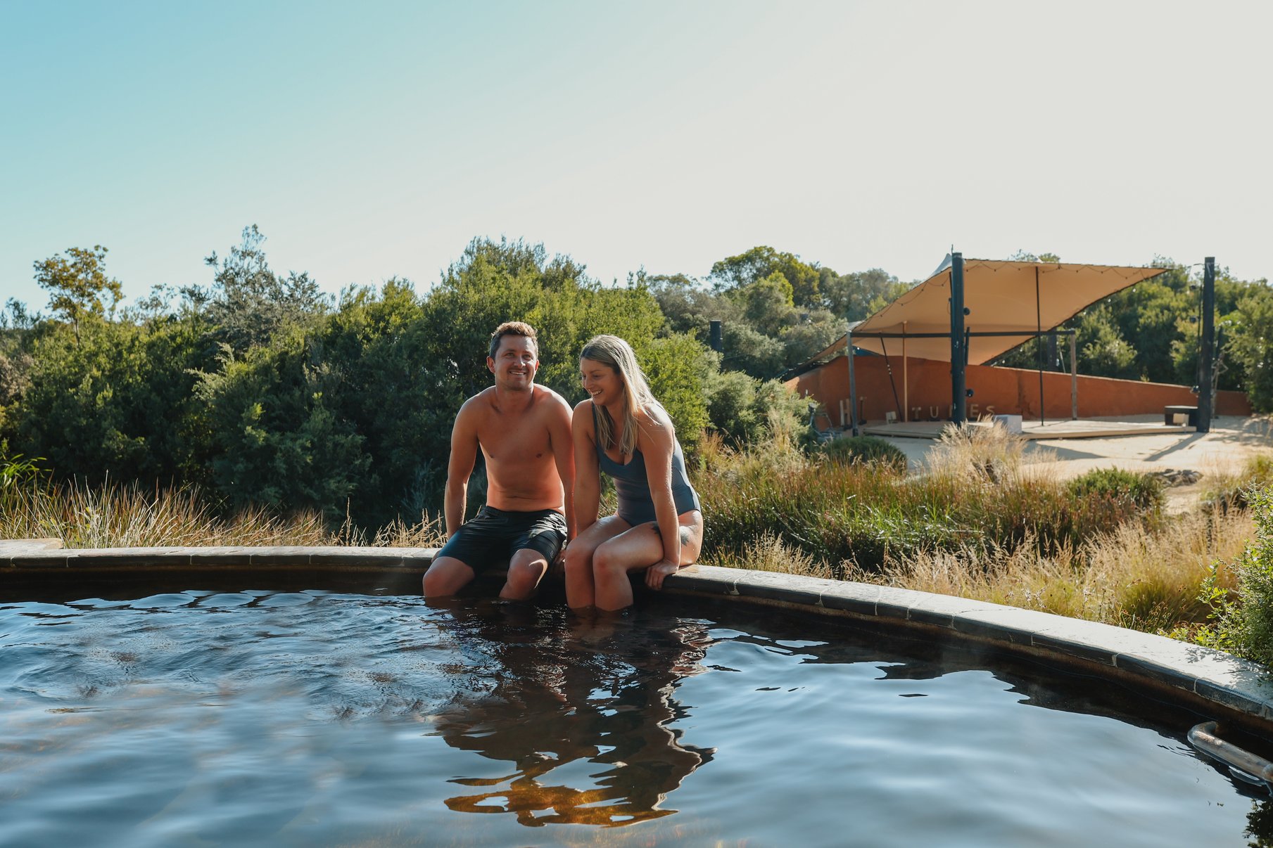 A couple sitting on the ledge of an Amphitheatre pool
