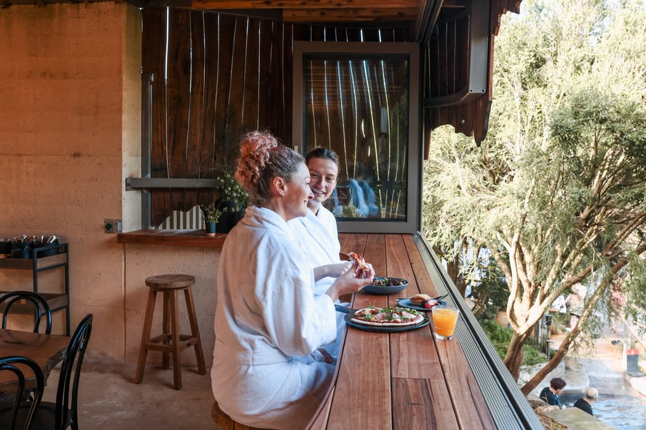 Two women sitting at a bench in white robes in the Amphitheatre Cafe