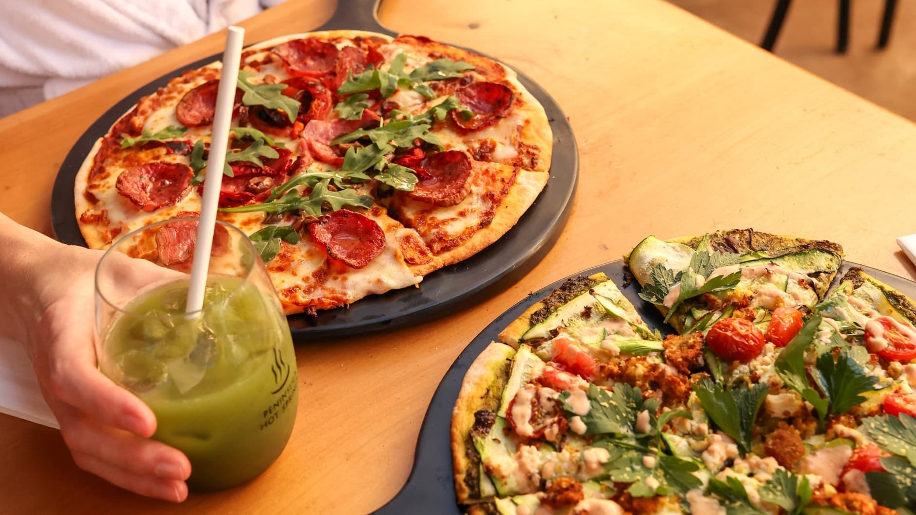Two gourmet pizzas and a glass of juice