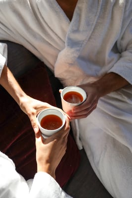 Two people in white robes drinking tea