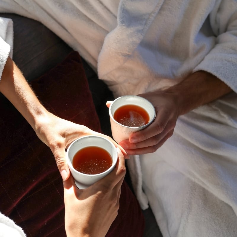 Two people holding a cup of tea in their hands