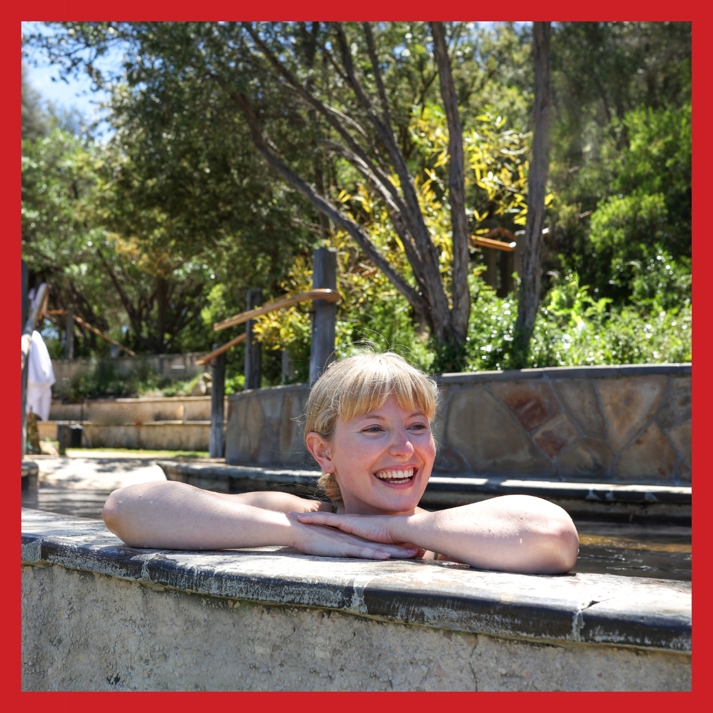 A person smiling and bathing in hot springs