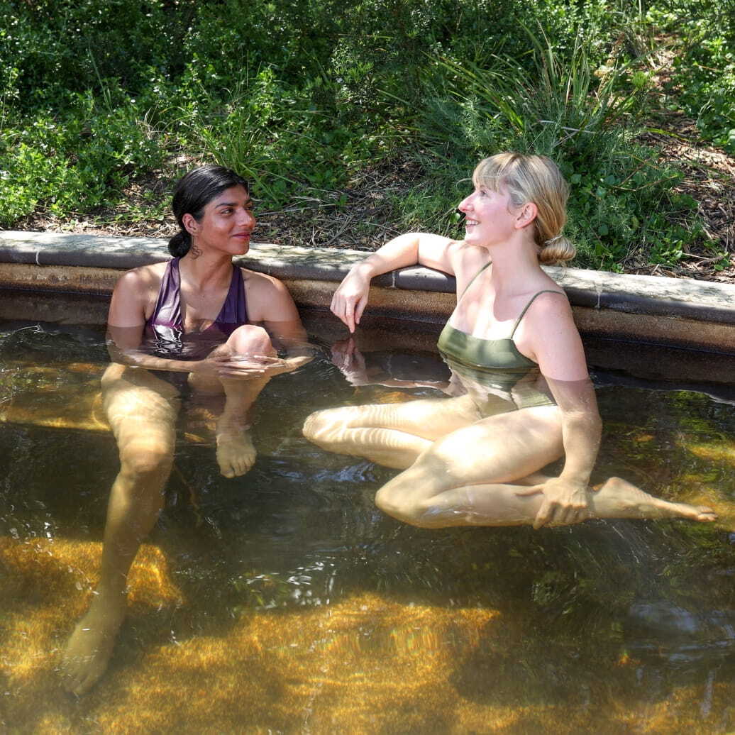 Two women laughing together while bathing in hot springs