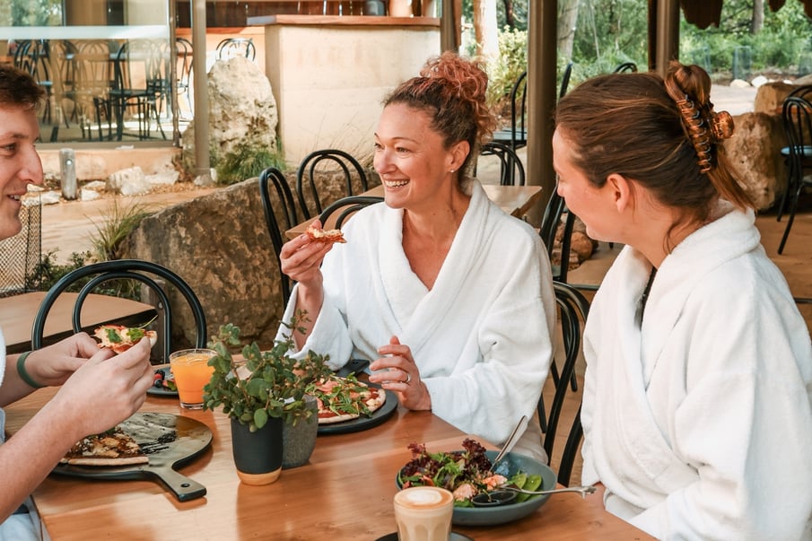 A group in white robes enjoying pizzas in the Amphitheatre Cafe