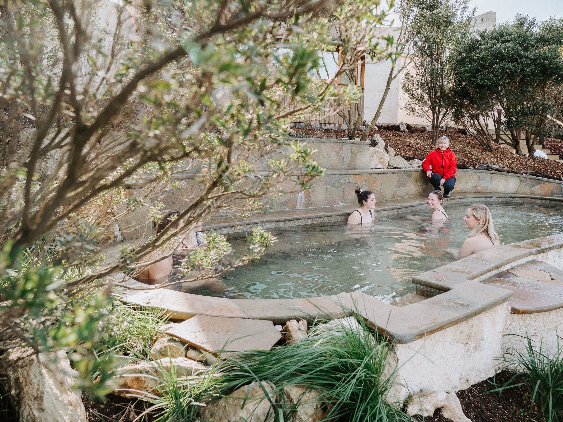 A pool attendant talking to a group of people bathing in hot springs