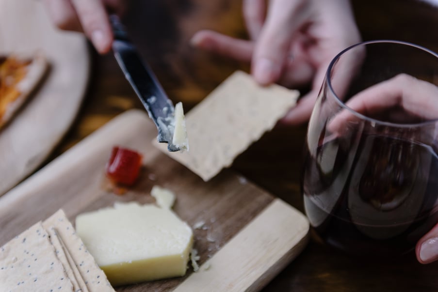 A person enjoying a cheese platter and glass of wine