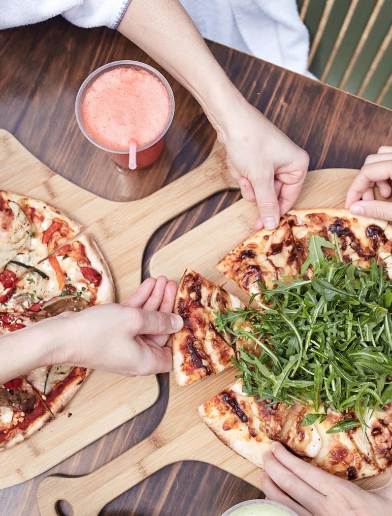 Two people enjoying a pizza and a juice