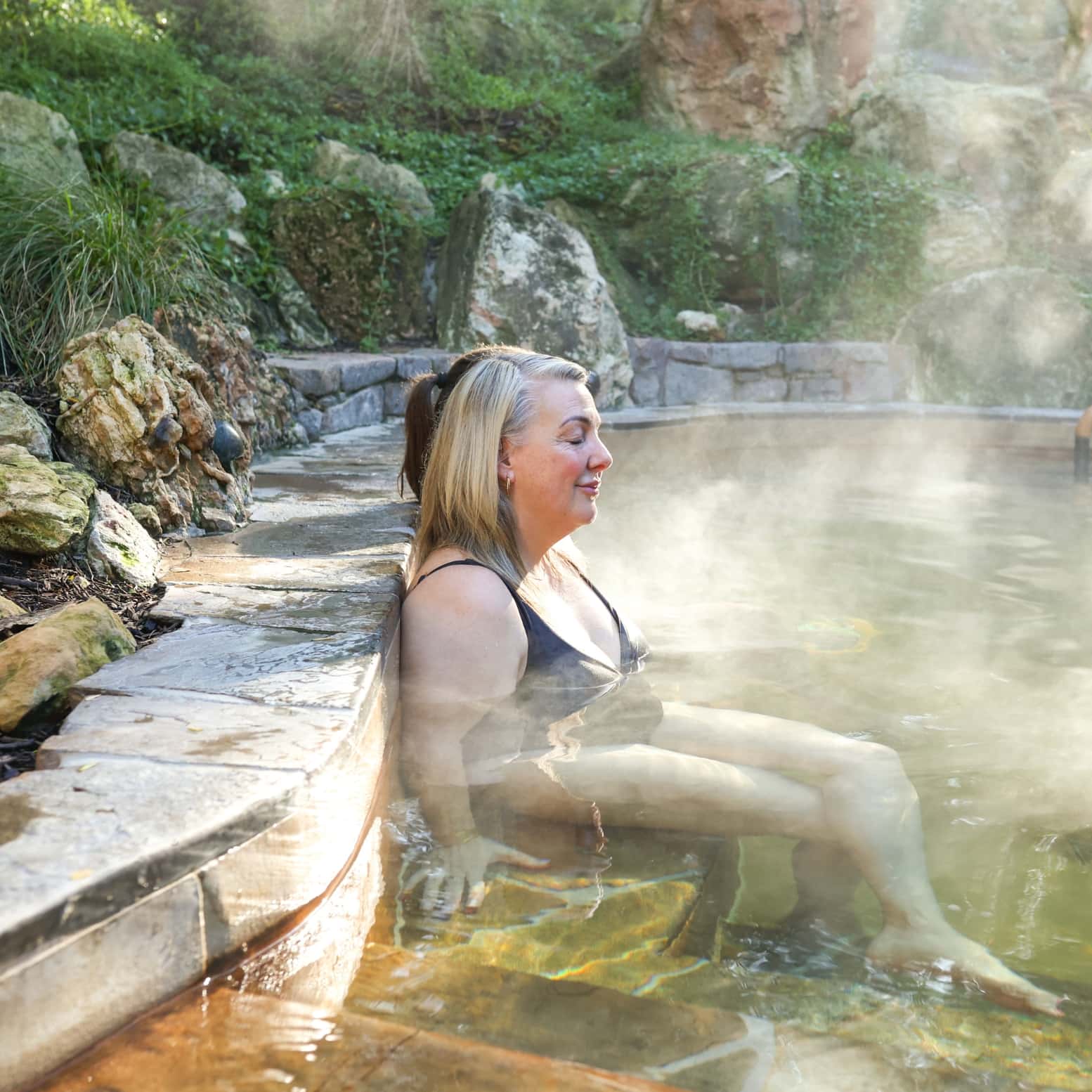Two women relaxing in hot springs with their eyes closed