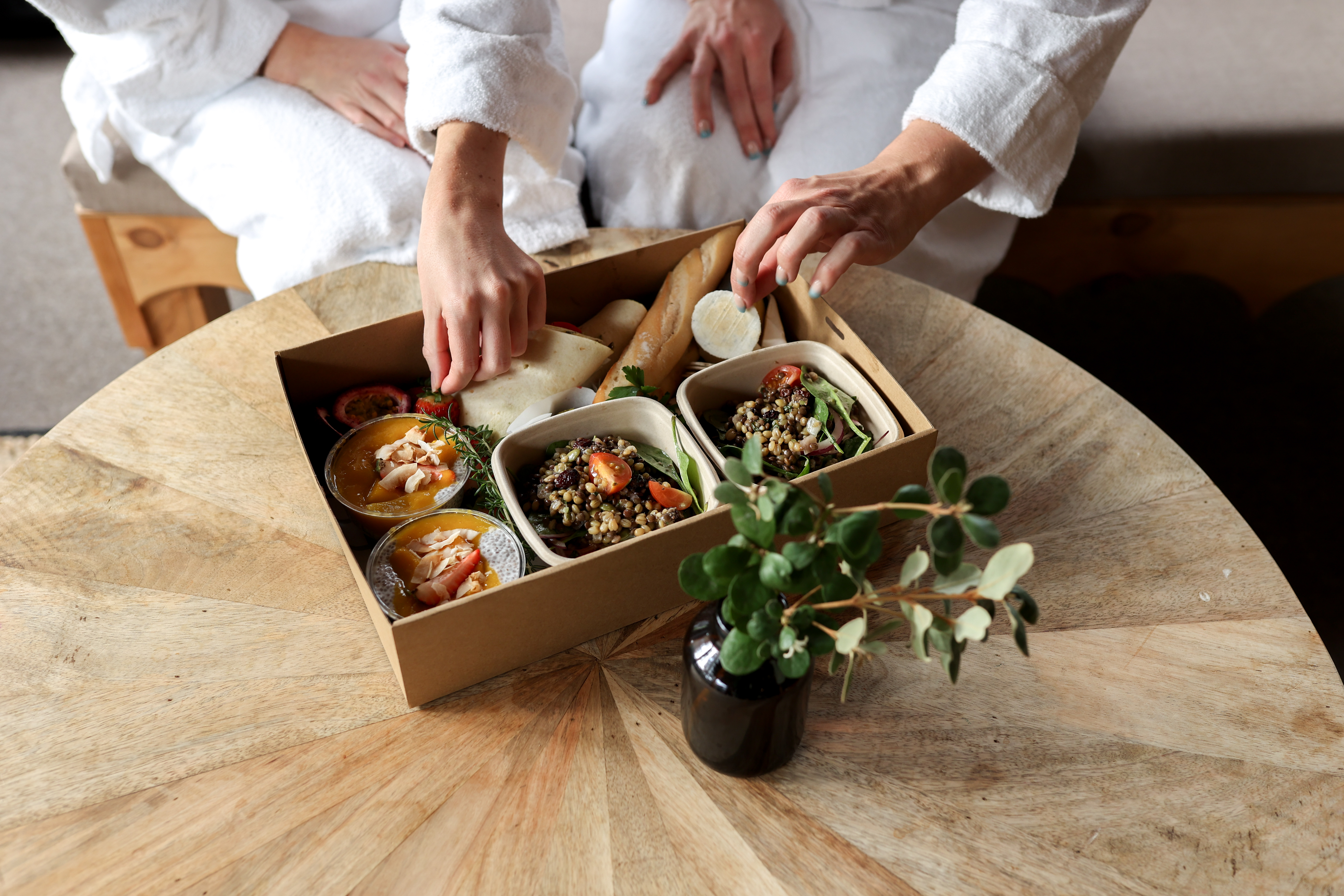 Two people in white robes eating from a picnic hamper prepared by Blue Mini