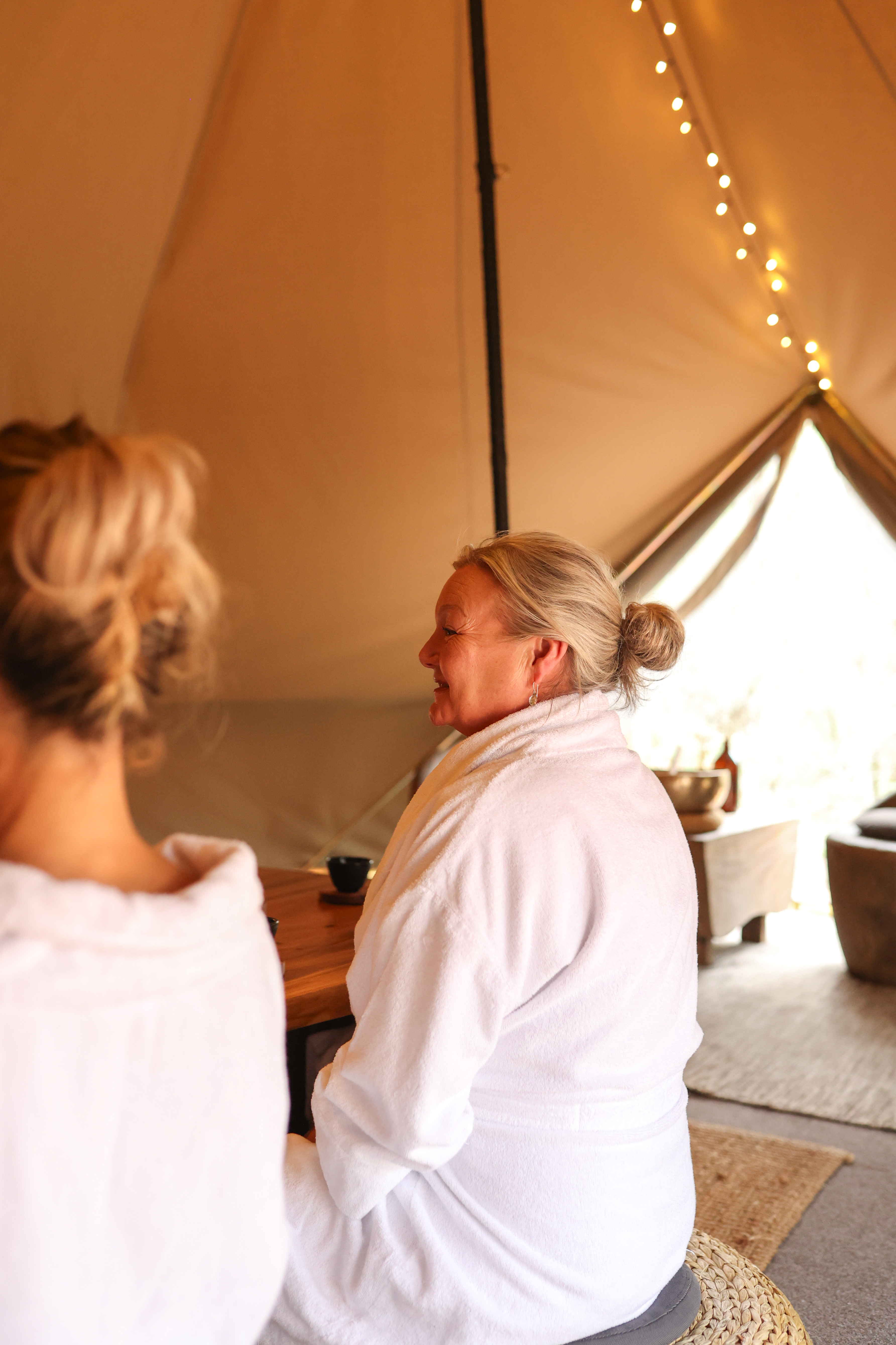 A woman sitting on a cushion in a white robe during the Cacao Circle
