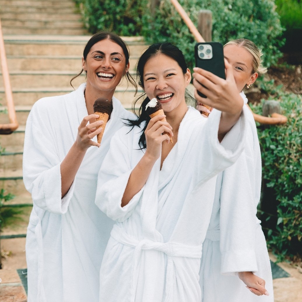 Three girls in robes eating ice creams