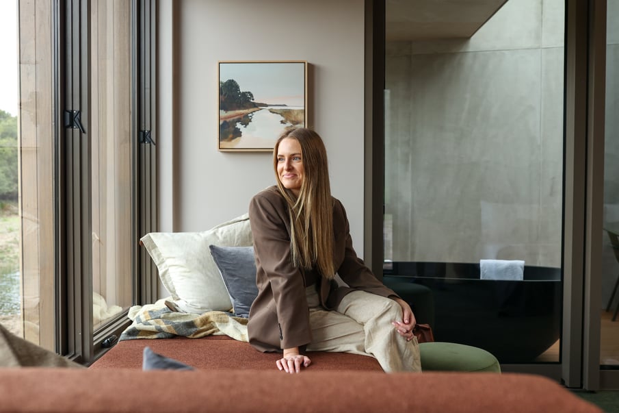 A woman sitting on a day bed in the Eco Lodges