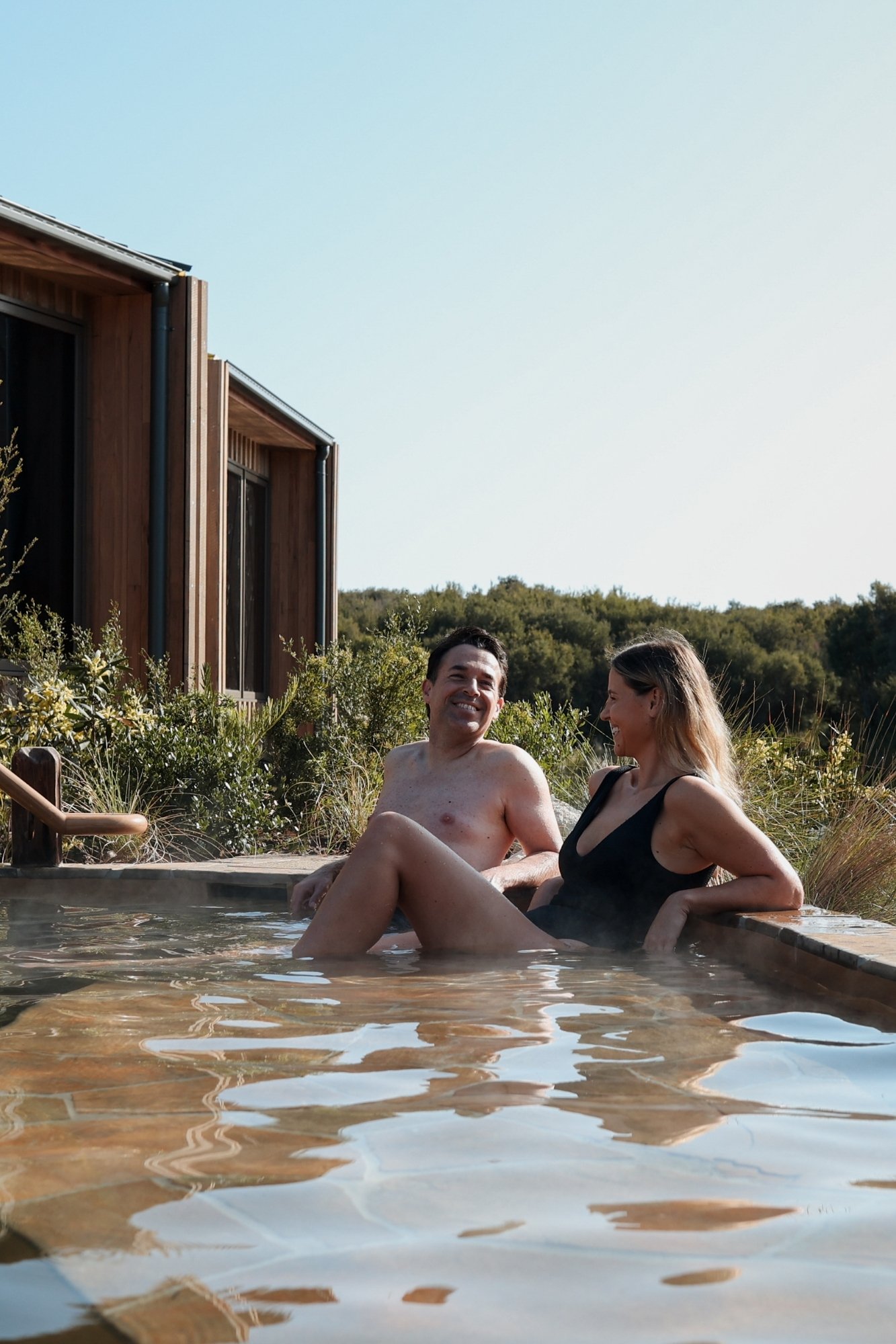 A man and woman sitting in the Eco Lodge Peninsula Suite hot spring pool