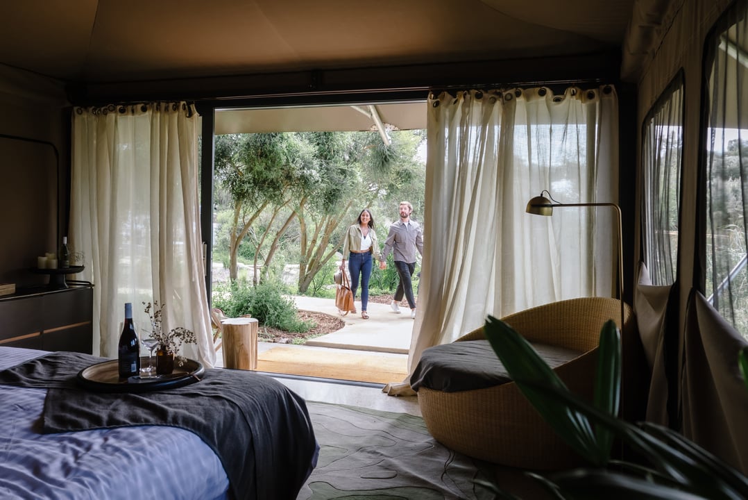 Two people walking into a Glamping tent