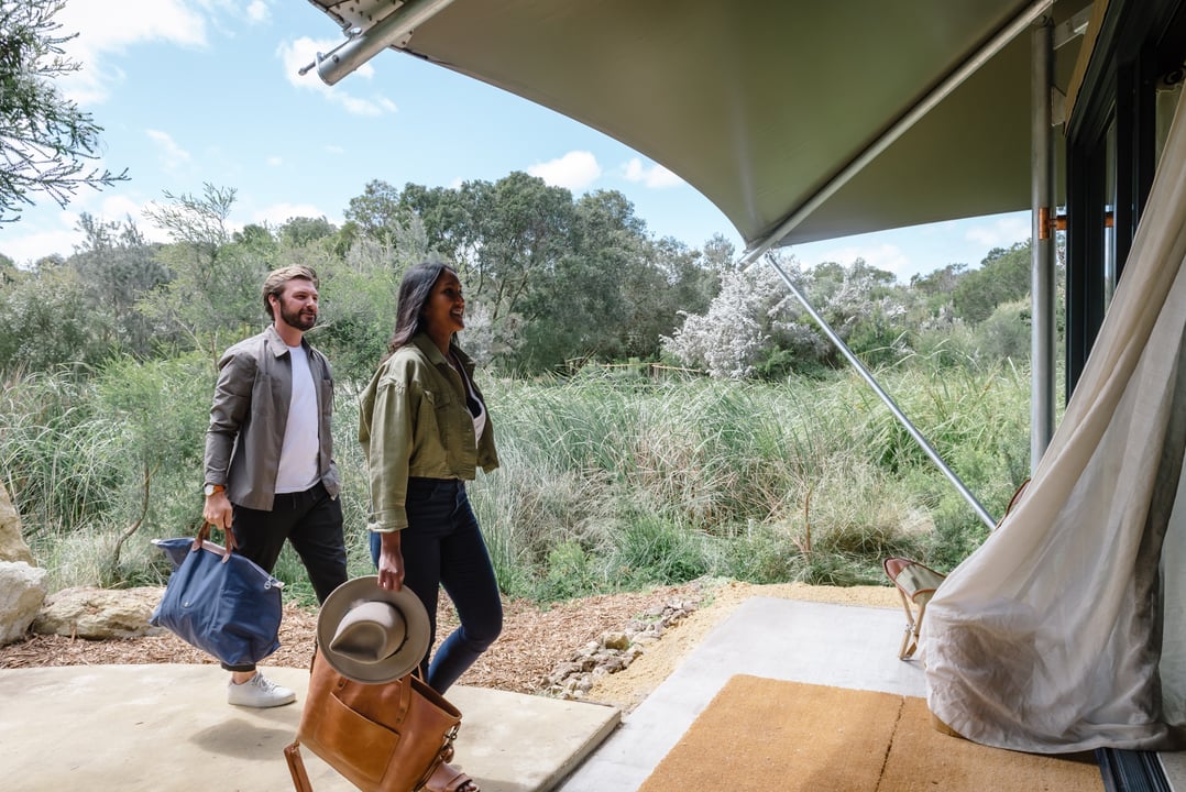 Two people walking into a Glamping tent