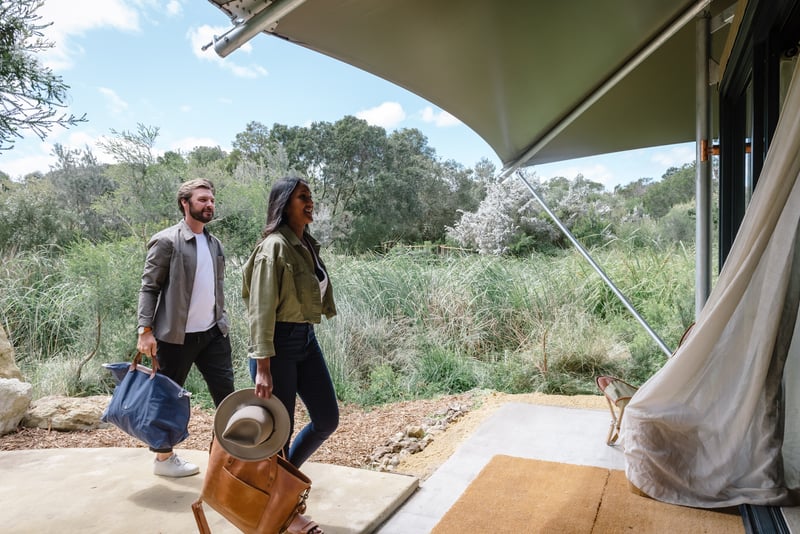 Two people walking into a Glamping tent