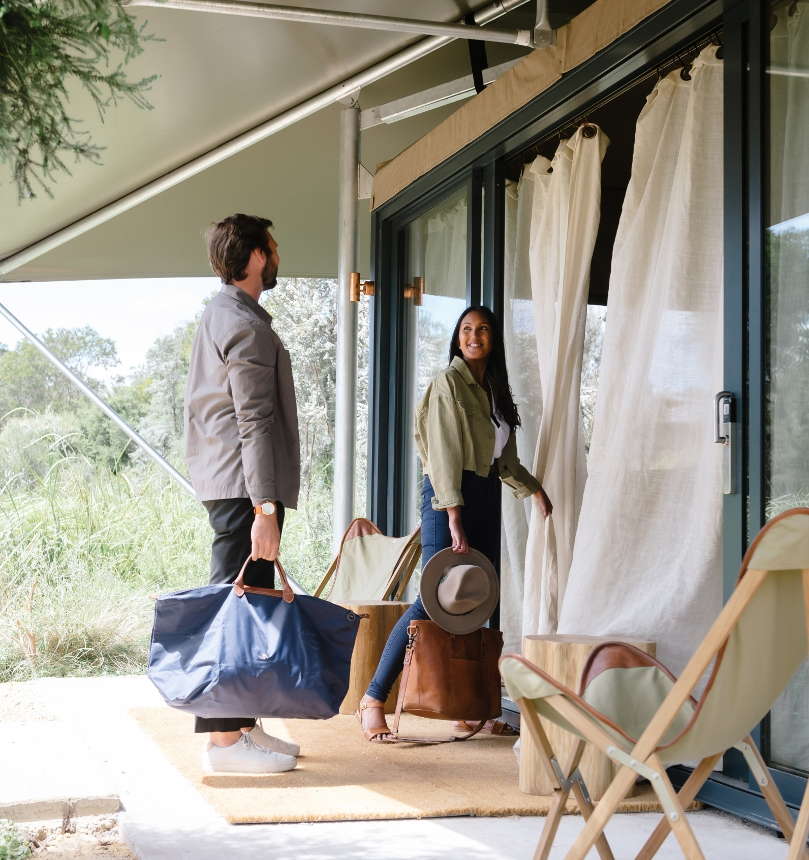 Two people with suitcases waling into a Glamping tent