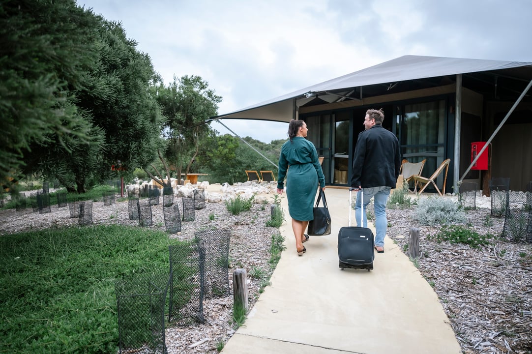 Two people in corporate attire walking to the Glamping tent