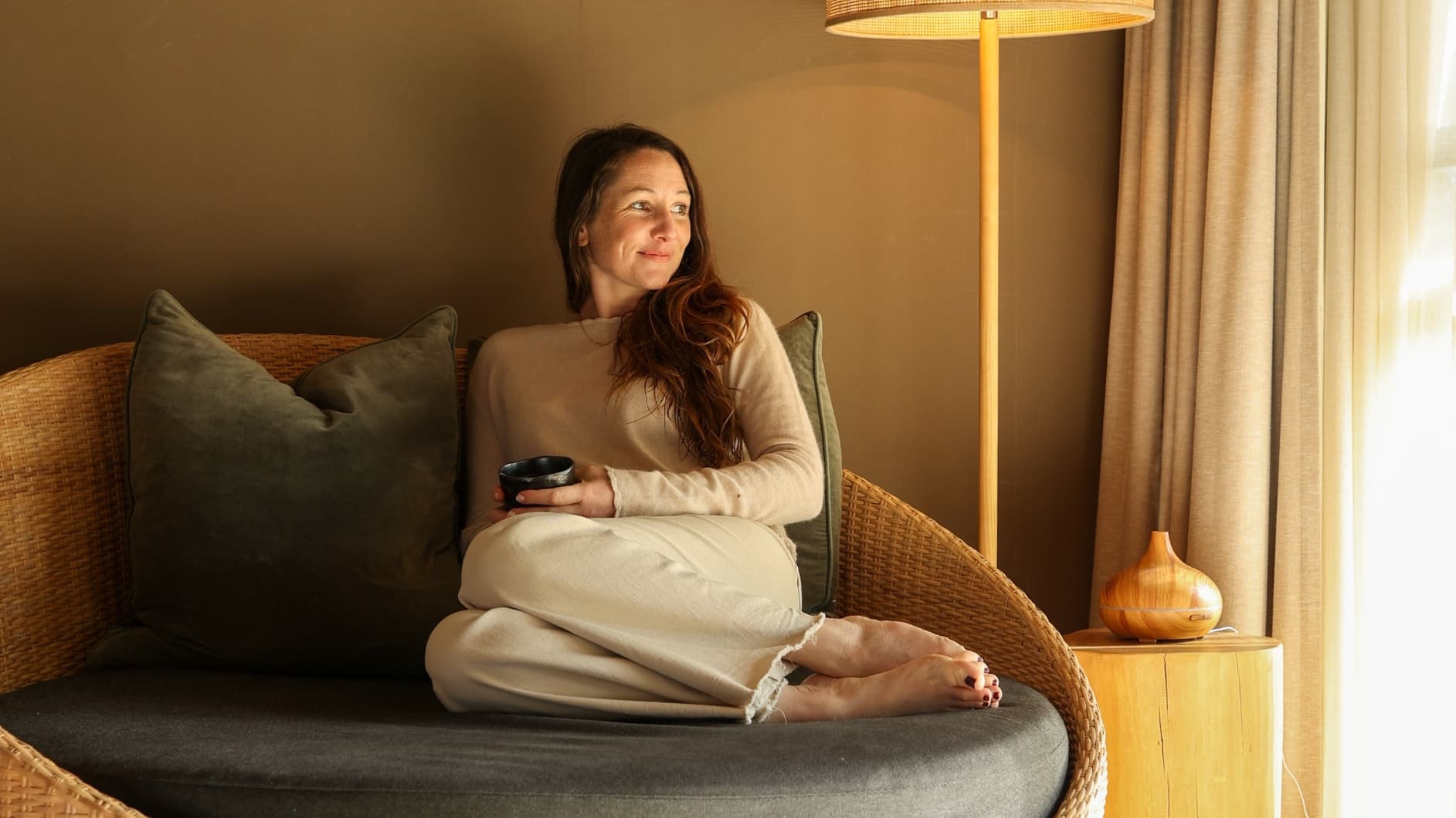 A woman sitting on a day bed in the Glamping tent