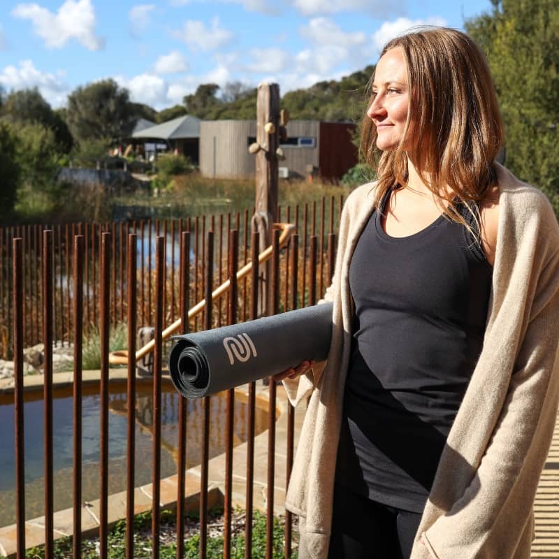 A woman holding a yoga mat while wearing workout wear from Inu8