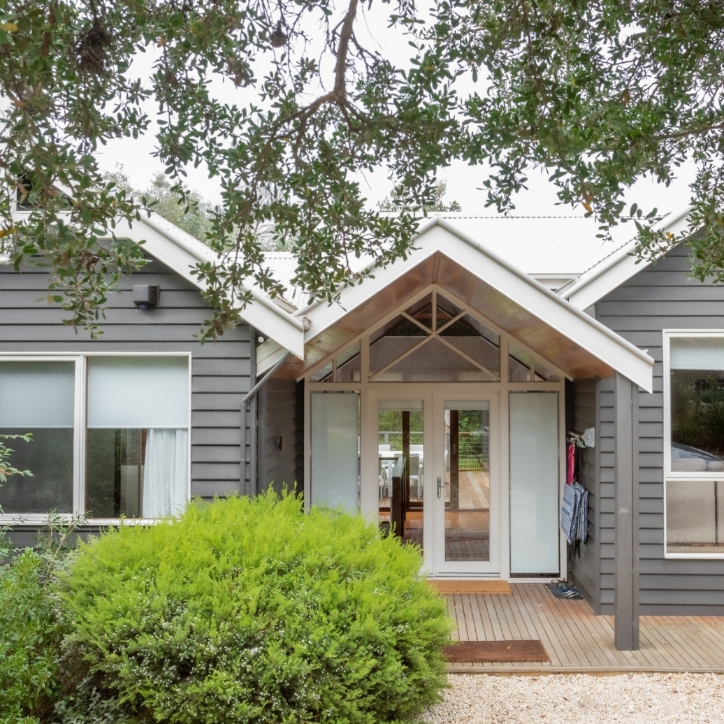 The exterior of a grey weatherboard cottage