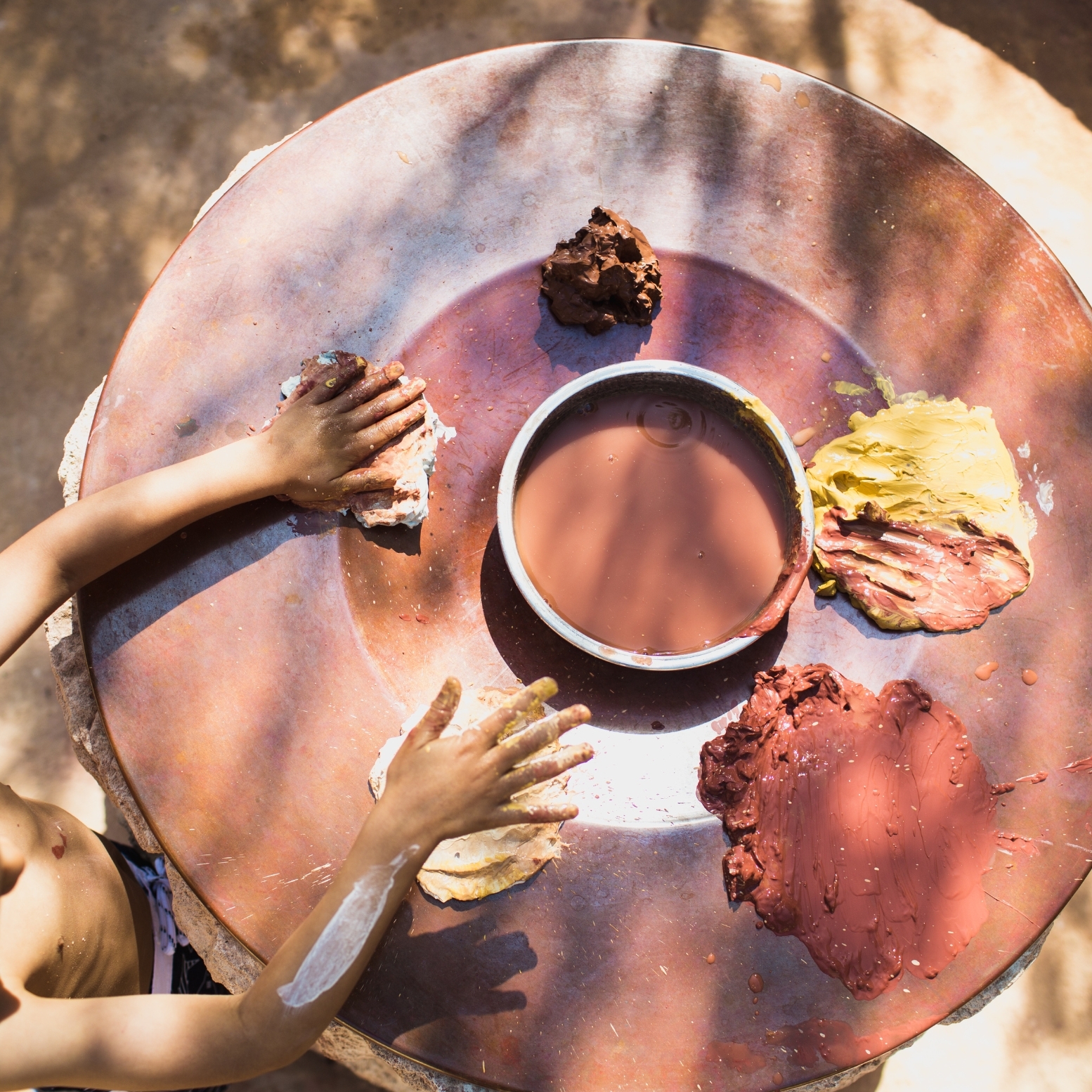 A young child putting their hands in clay