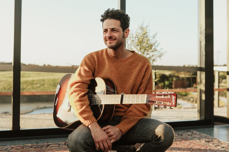 Music artist Lior holding a guitar in the Glasshouse