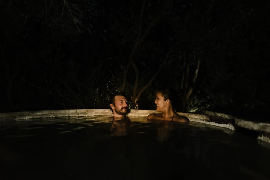 Two people bathing in hot springs in the evening