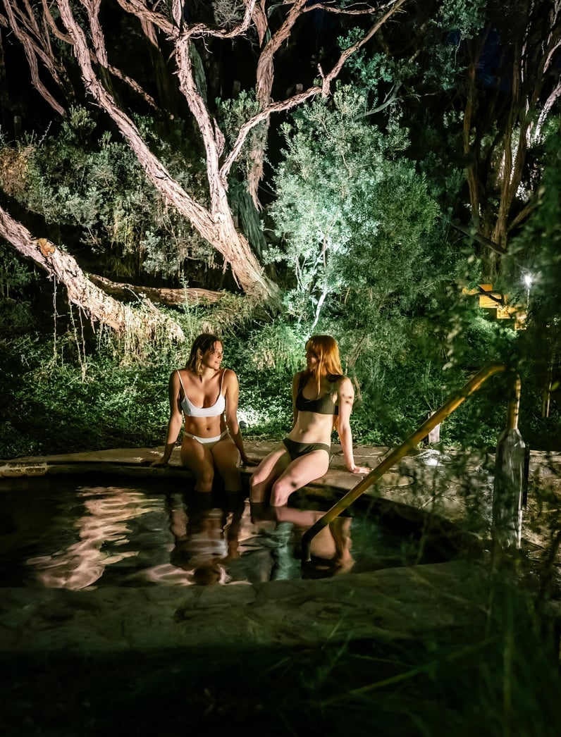 Two young women dangling their feet in hot springs during Moonlit Bathing