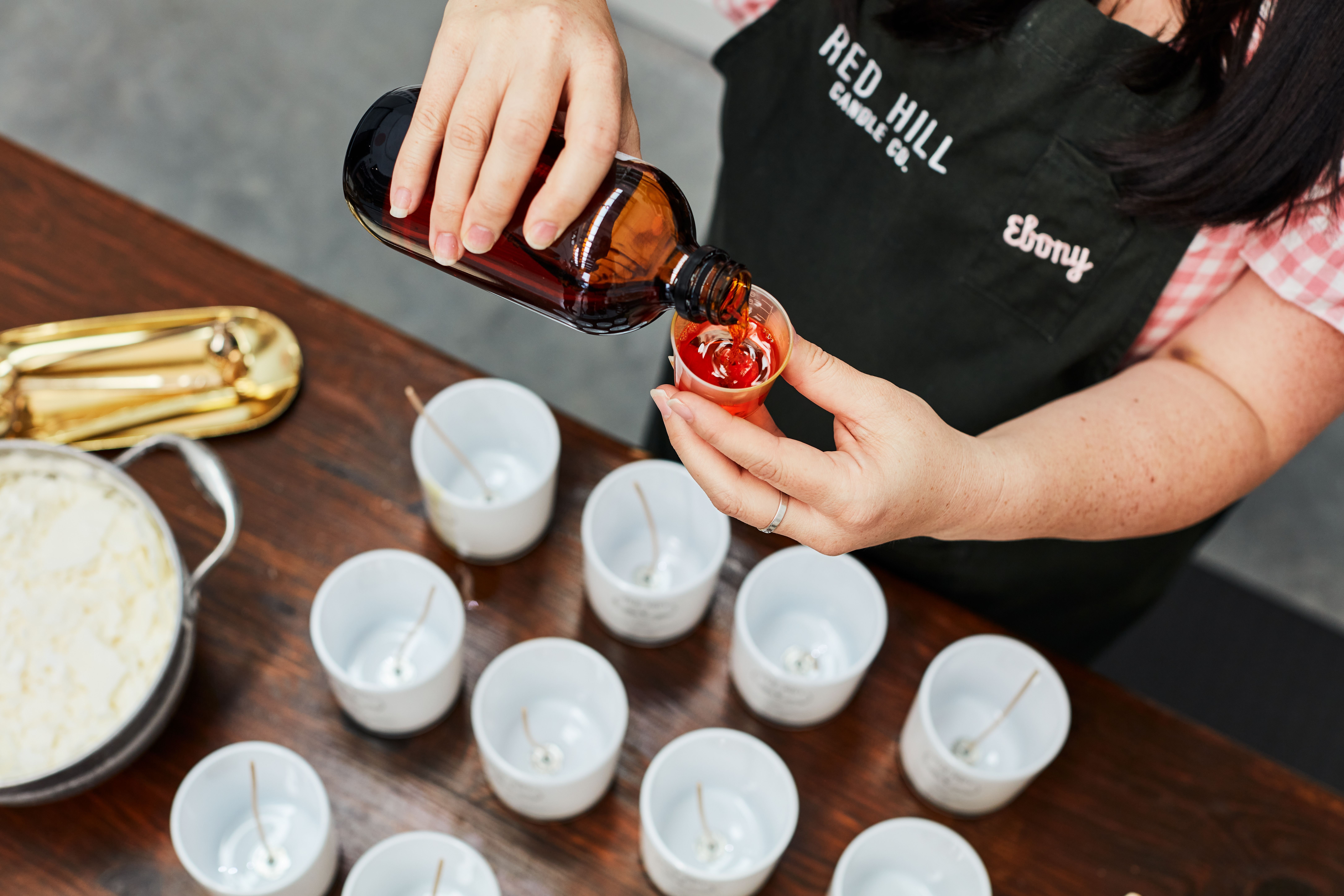 A person pouring wax into a selection of candles