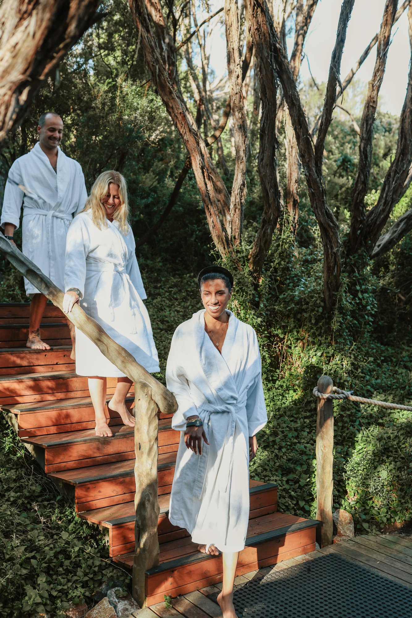 Three people in white robes walking on a path in Spa Dreaming Centre