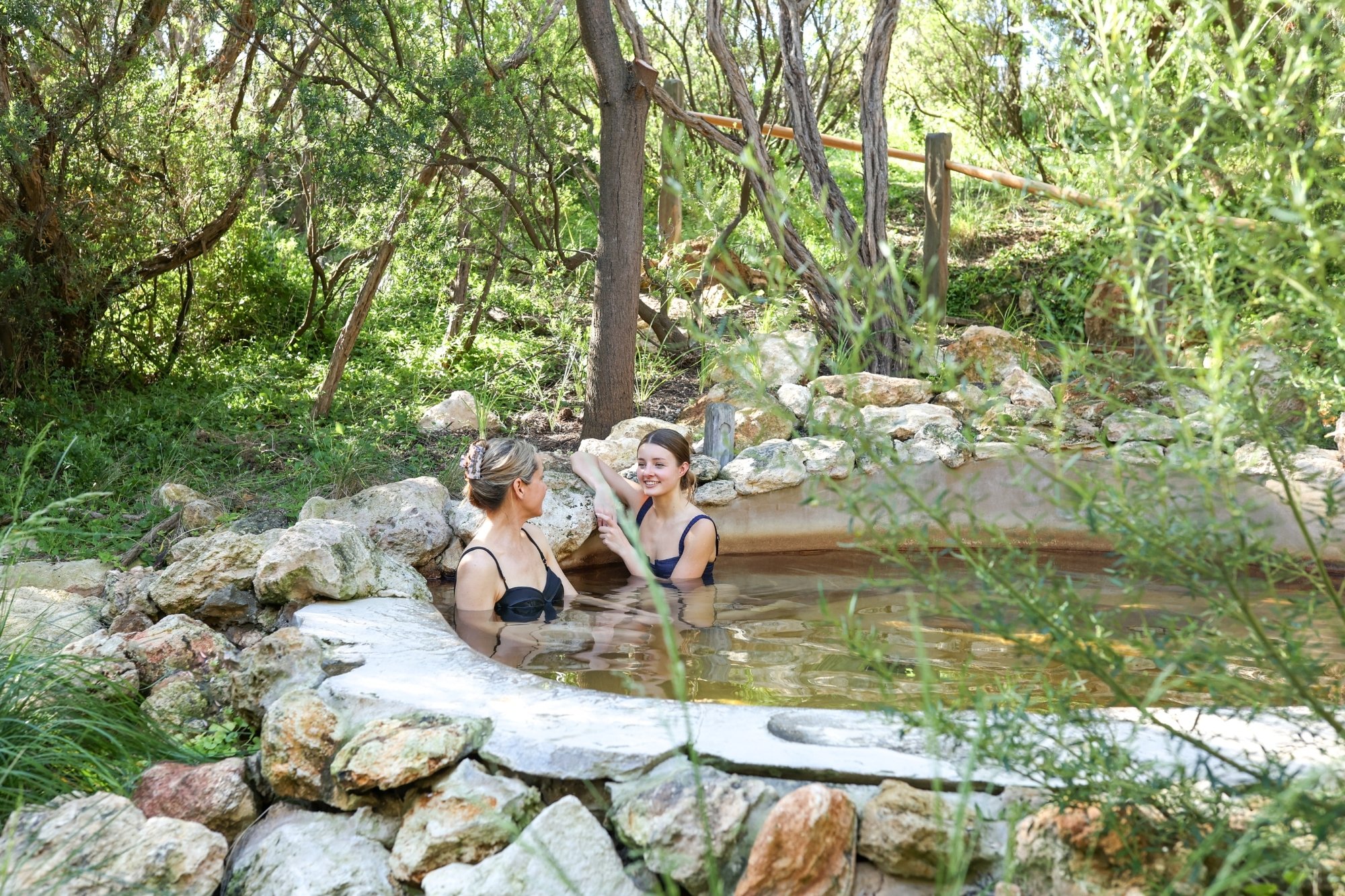 Two people bathing in hot springs amongst nature