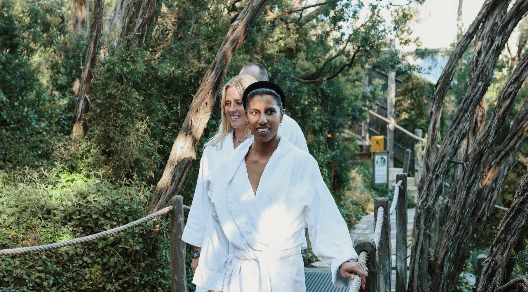 Three people in white robes walking through the SDC