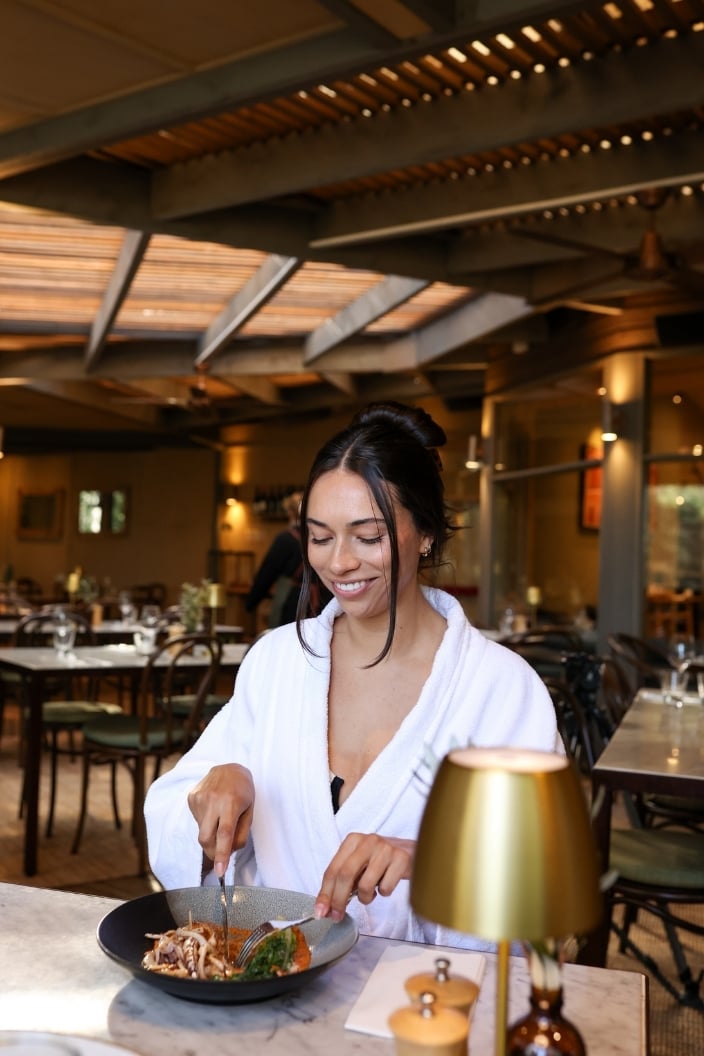 A woman in a white robe eating a seaonsal plate of food in the SDC Dining room