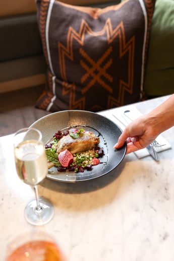 A person placing a plate on a marble table in the dining room