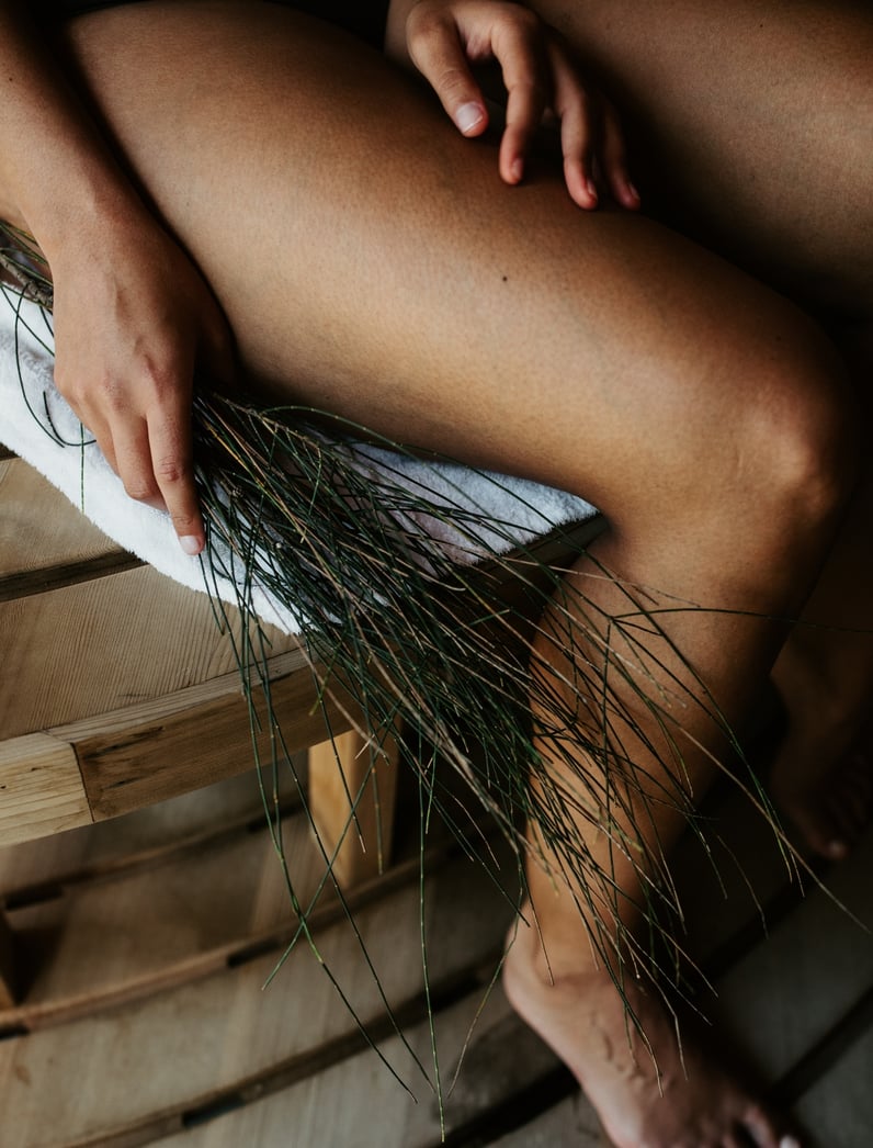 A woman holding a sauna whisk