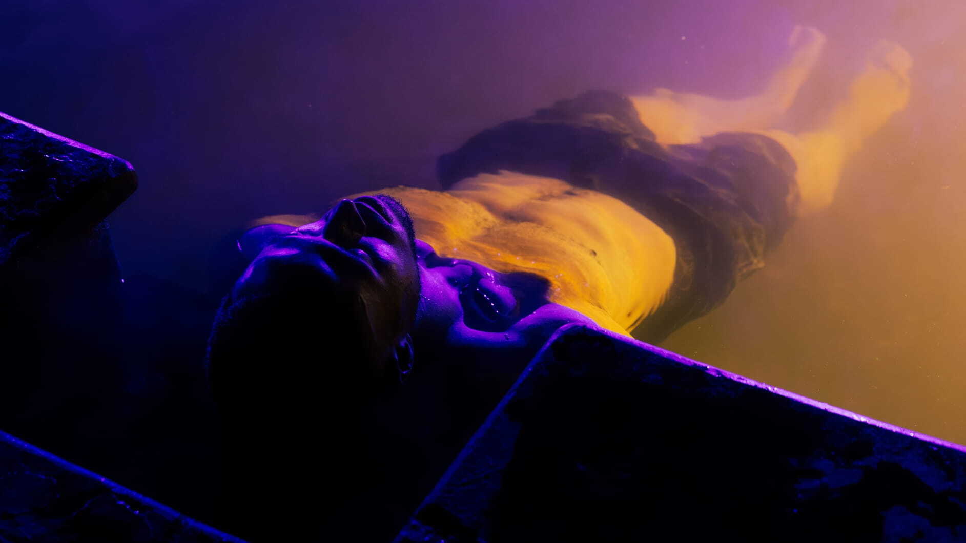 A man lying in an indigo-lit pool as part of the Seek the Heat campaign