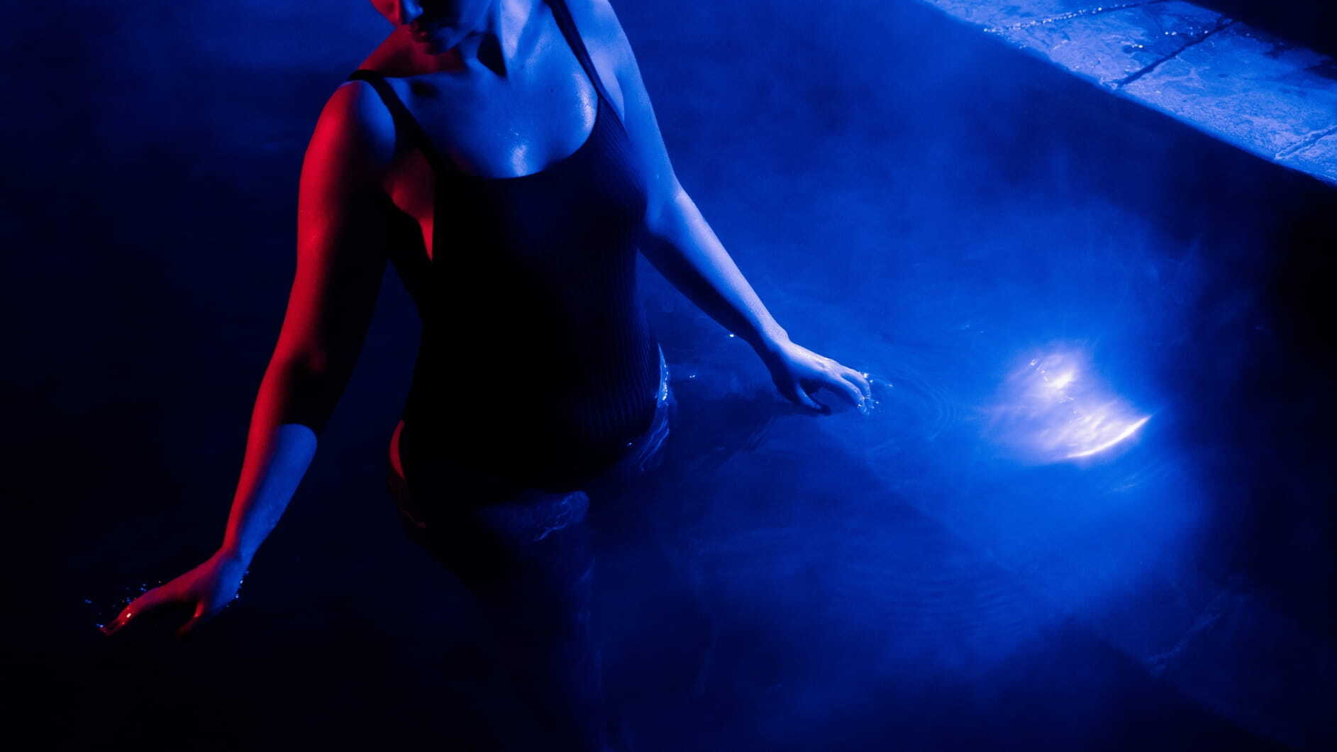 A woman moving through a blue lit pool as part of the Seek the Heat campaign