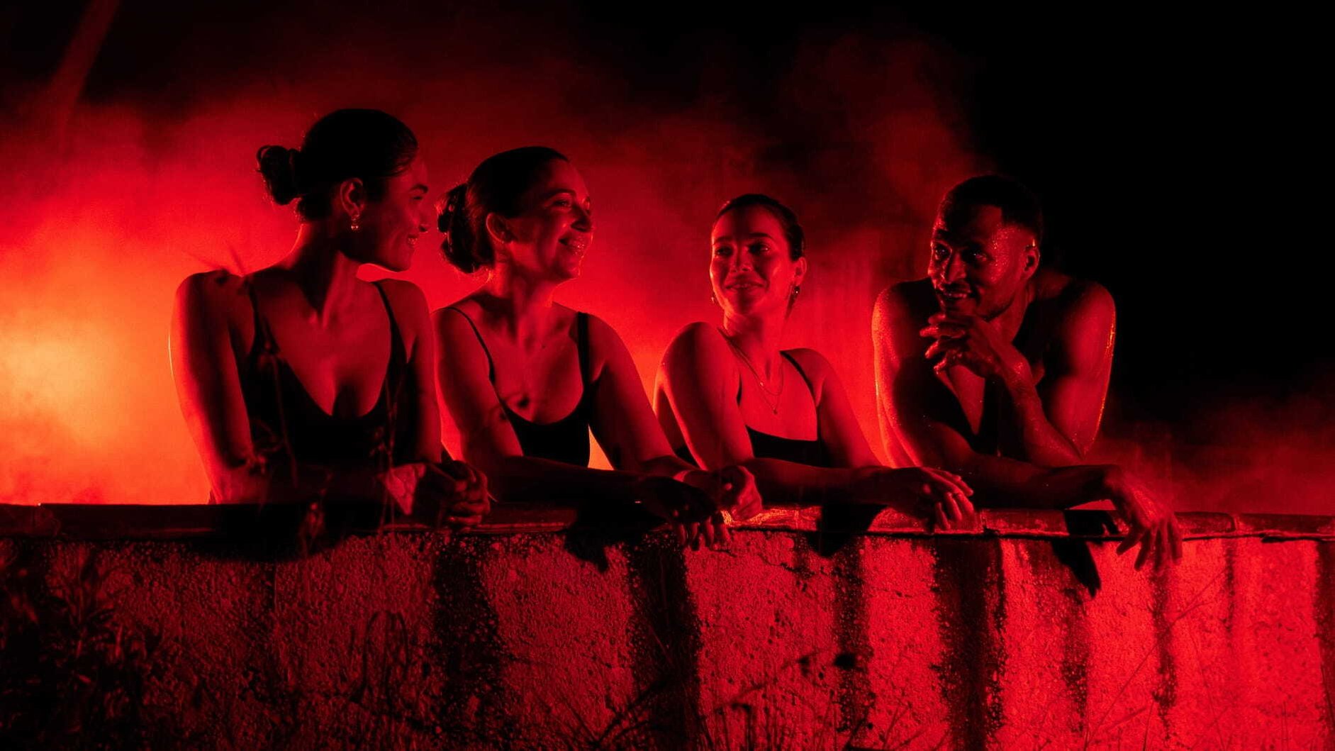 A group of people in a pool that is lit up in red lights as part of the Seek the Hear cmapaign