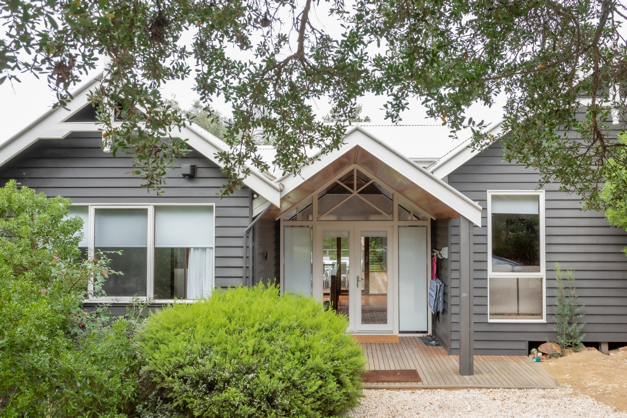 The exterior of a grey weatherboard cottage