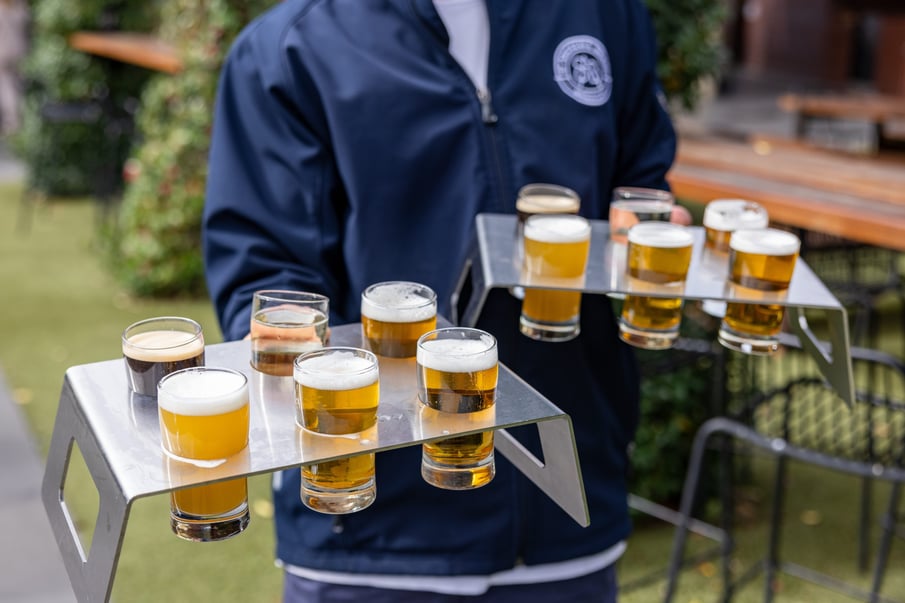 A person holding beers in a metal tray