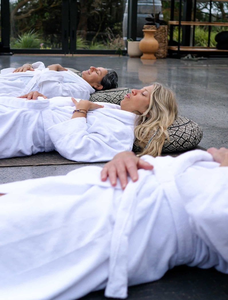 Three people laying down in robes during a Stretch and Breathe class