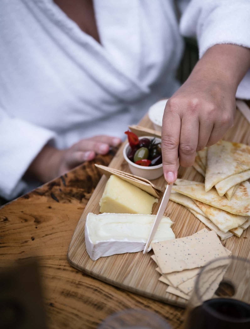A person in a white robe enjoying a grazing board