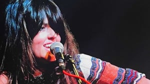 Local artist Michelle McManus singing through a microphone on stage