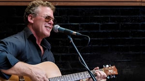 Pete Miller performing on stage with an acoustic guitar