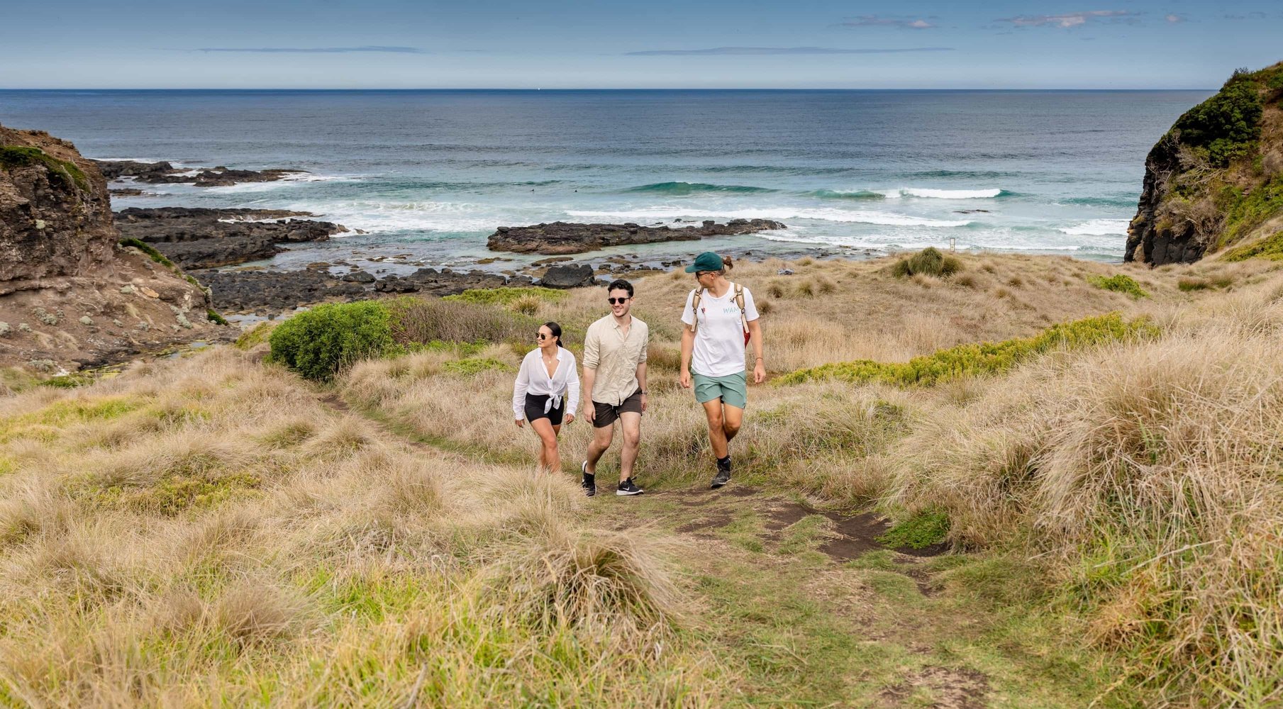 Three people walking on the coastline