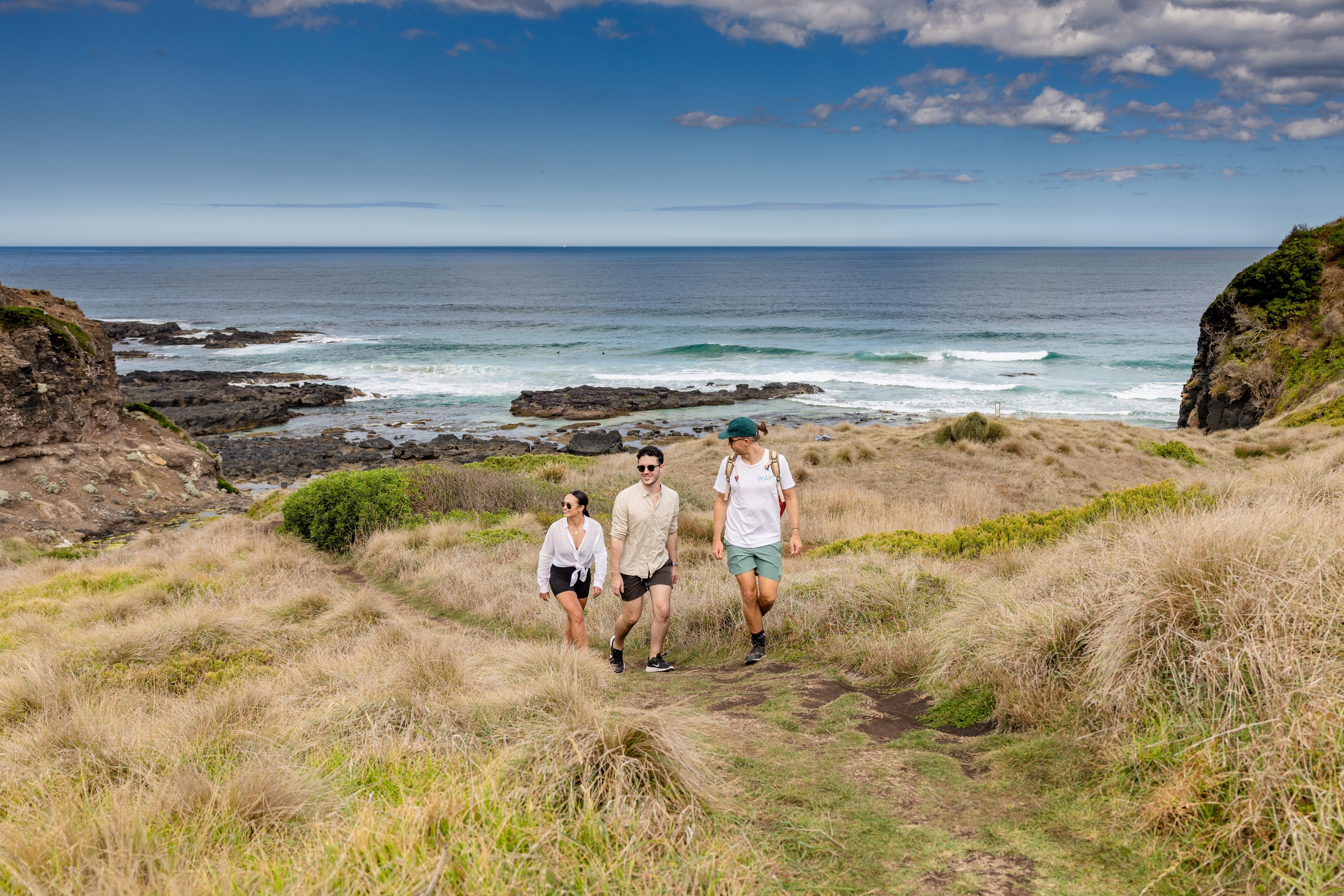 Three people walking through coastal bushland on the Mornington Peninsula